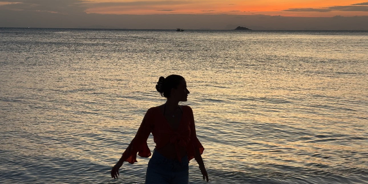 Frau am Meer während des Sonnenuntergangs