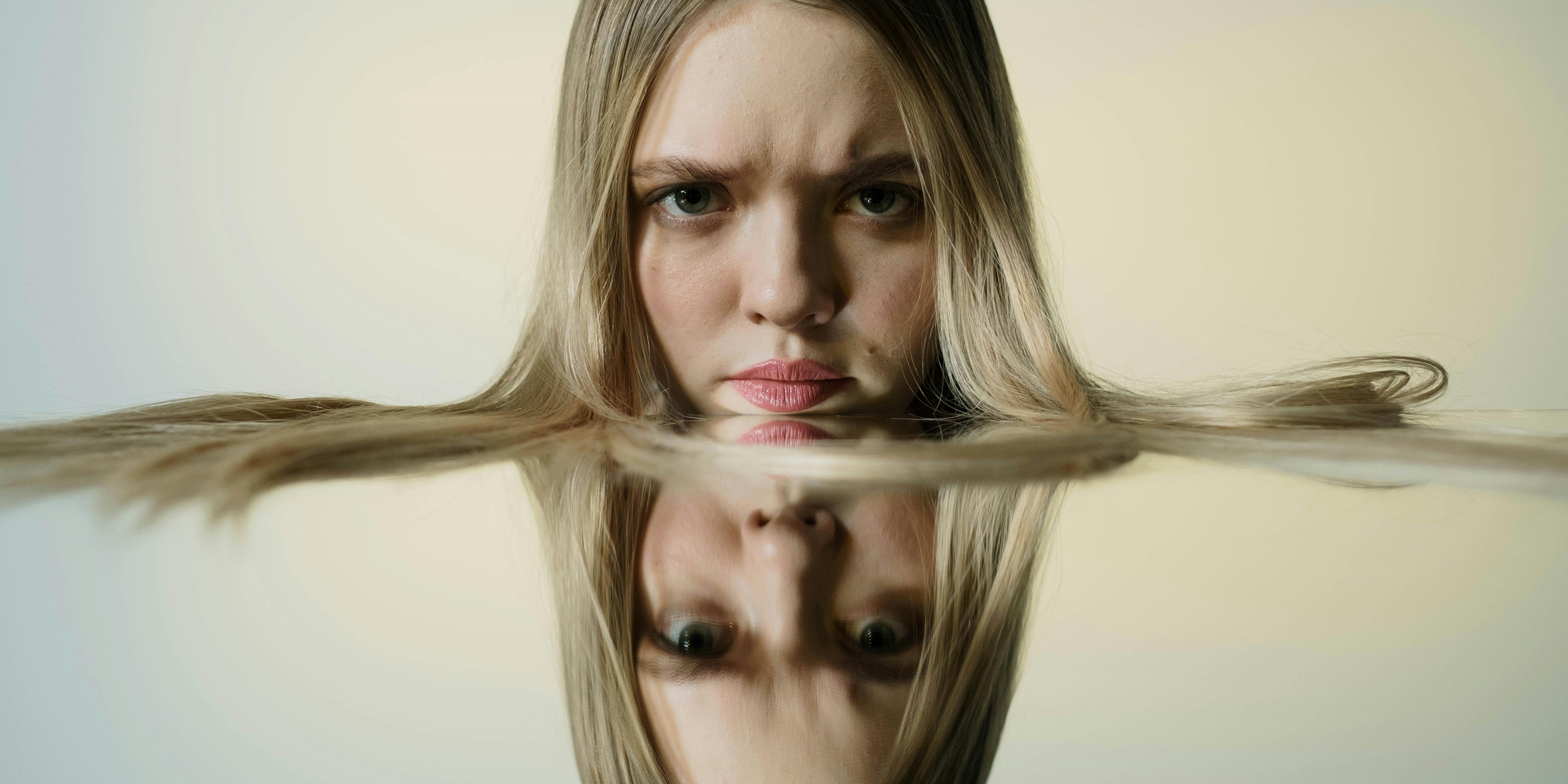 Blonde Frau mit angespanntem Gesicht, dass kopfüber gespiegelt wird.