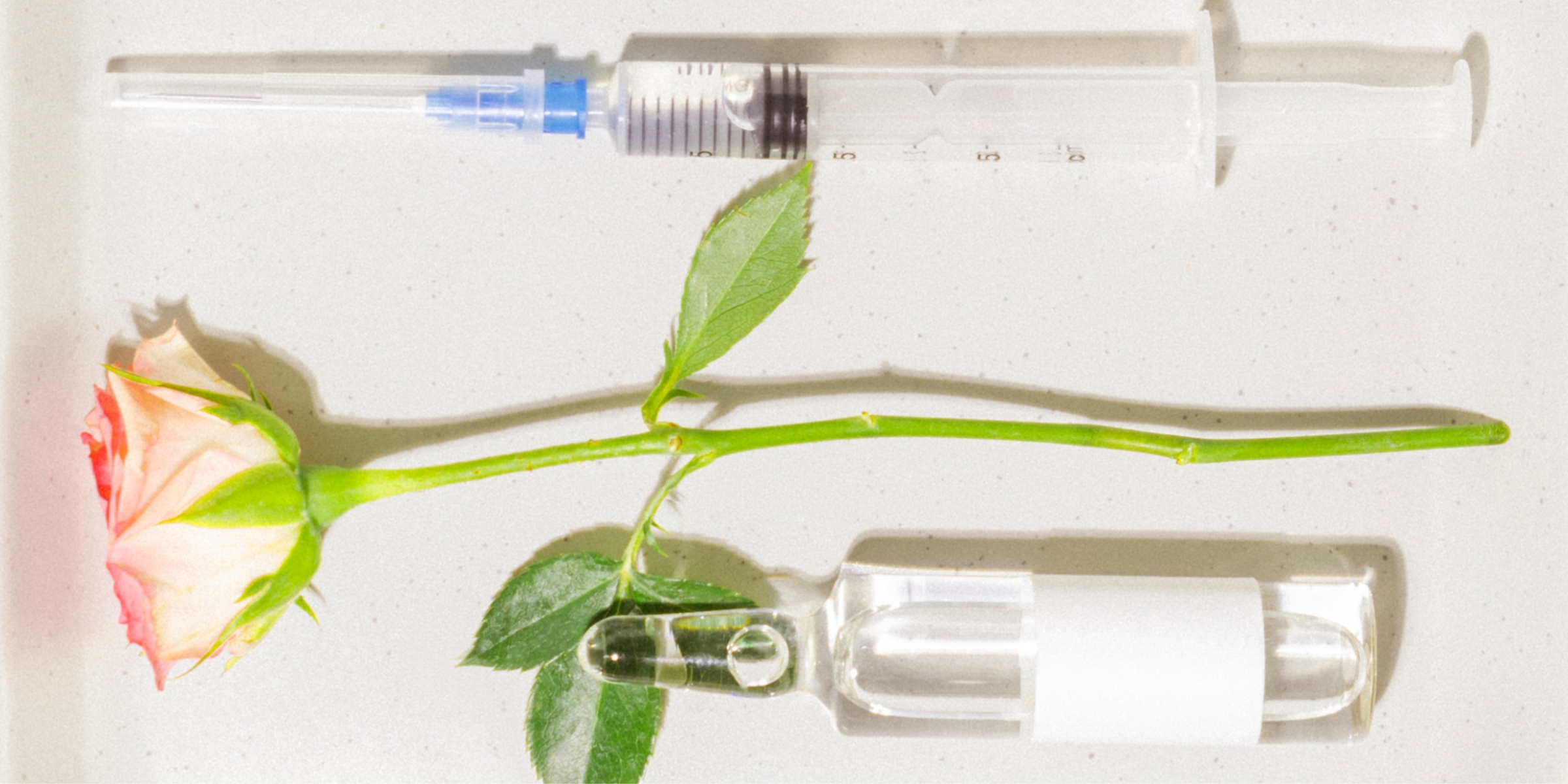 Botoxspritze, eine Rose und eine Ampulle auf einer Schale.