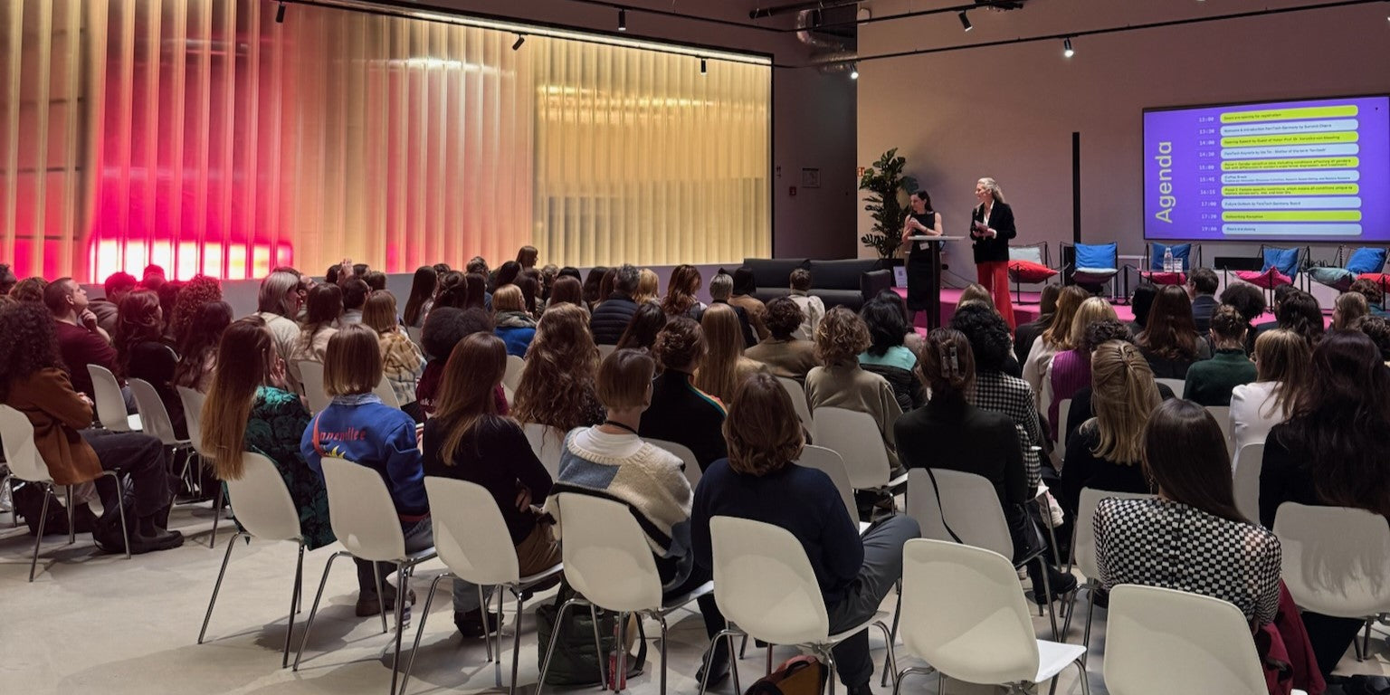 Frauen die bei einem Summit in Reihen sitzen und zwei Frauen auf der Bühne zuhören