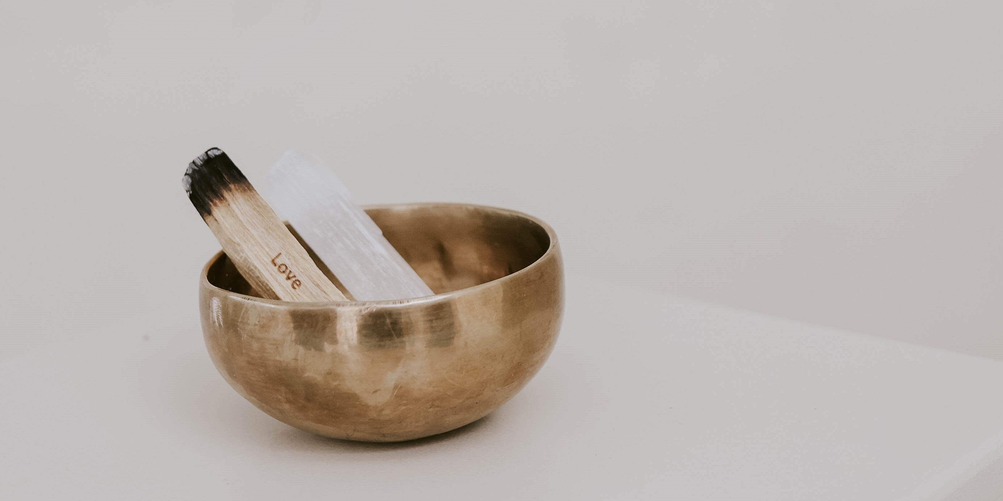 Angezündetes Palo Santo und ein Selenitstab in einer Klangschale