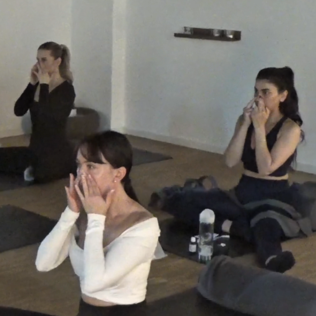 Drei Frauen, die auf den Yogamatten von yardin zayel sitzen im Schneidersitz und ihre Lymphe im Gesicht mit den Händen öffnen während der Gua Sha Session. 