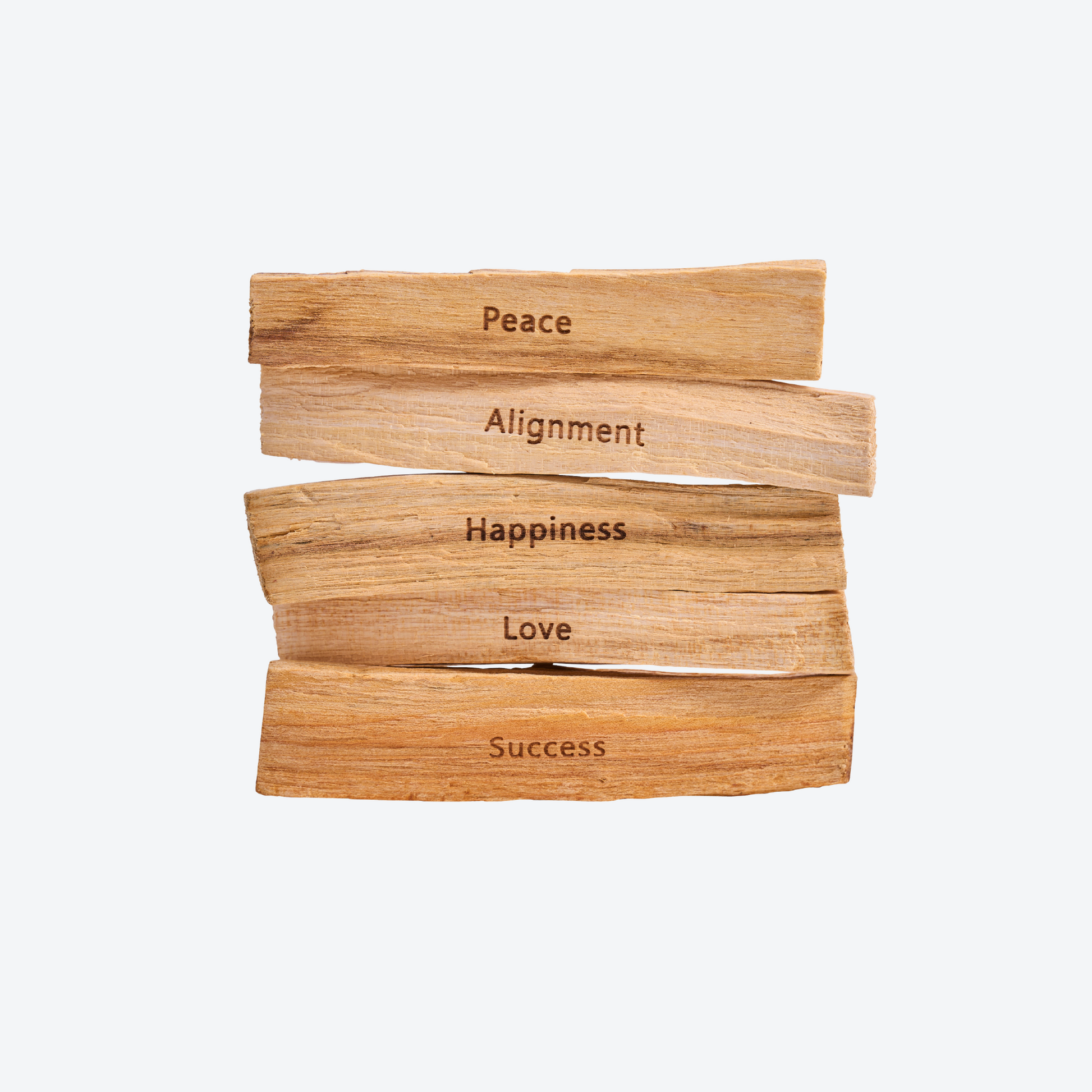 Freistellerbild von gestapelten Palo Santo Hölzern, jedes mit einem Mantra: Peace, Alignment, Happiness, Love und Success.