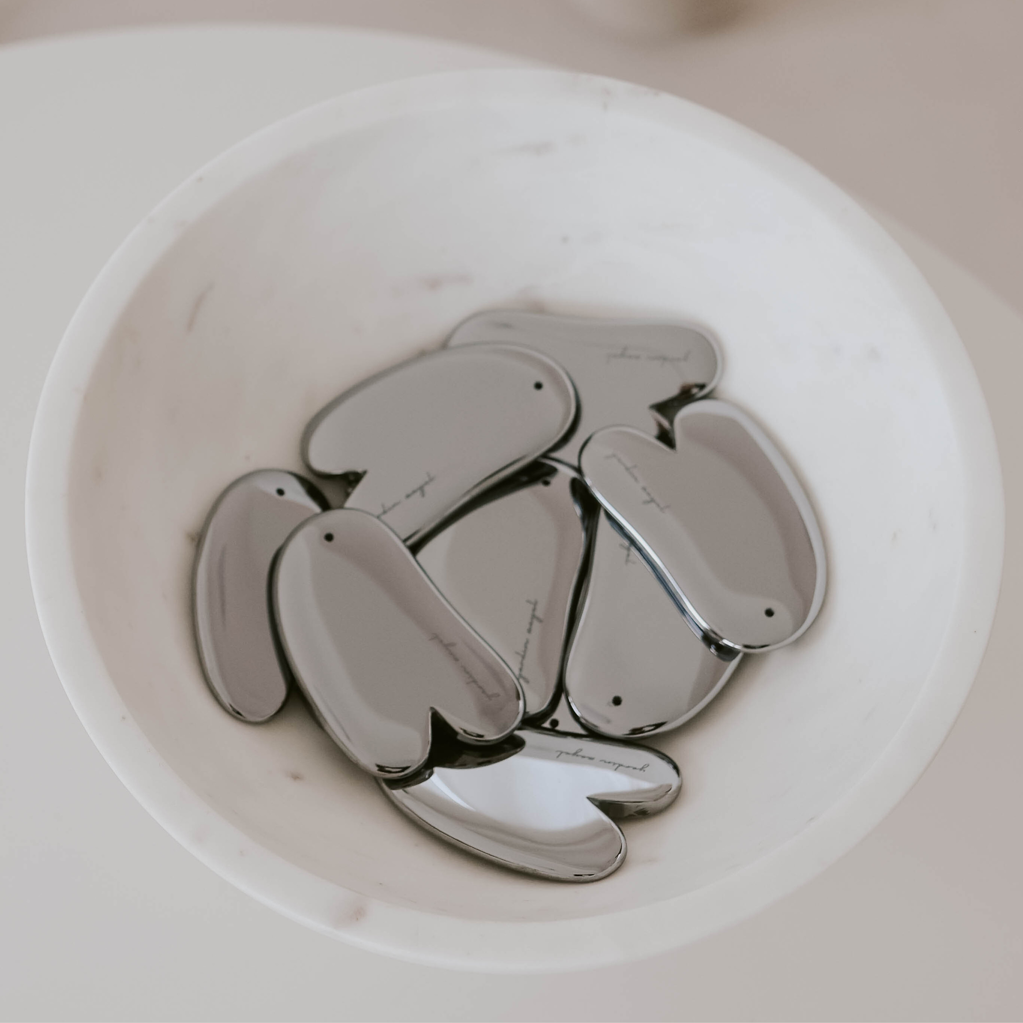yardin zayel Teaglow Gua Sha aus Terahertz-Material. Mehrere in Marmorschale als ruhiger Ästhetik-Shot